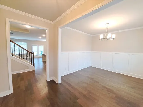 an empty room with wooden floor and chandelier