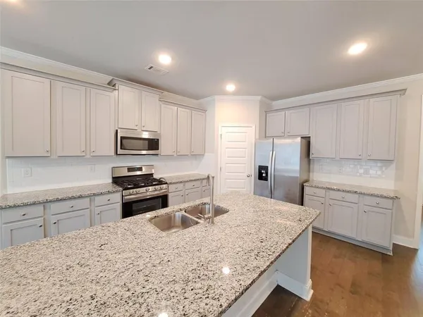 a kitchen with stainless steel appliances granite countertop a sink stove microwave and refrigerator