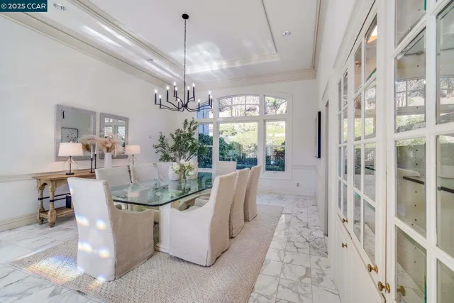 a view of a dining room with furniture a chandelier and large windows