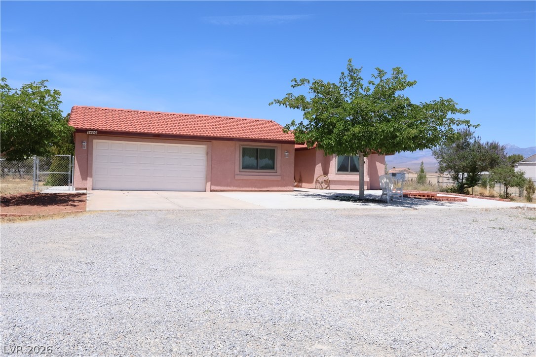 1220 East Gamebird Road Pahrump, NV 89048 - Photo 2 of 49 A terracotta-tiled roof crowns this desert-hued abode with a wide, gravel forecourt leading to a convenient attached garage.