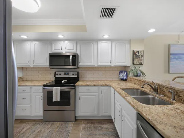 a kitchen with granite countertop a sink stainless steel appliances and cabinets