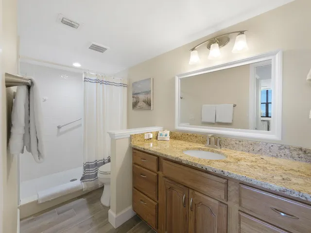 a bathroom with a granite countertop sink mirror and toilet