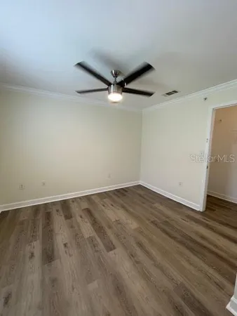 an empty room with wooden floor and a ceiling fan
