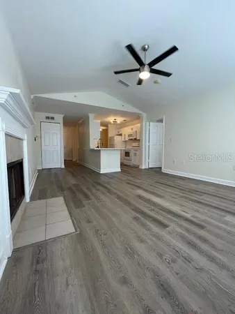 a view of a livingroom with a fireplace a ceiling fan and wooden floor