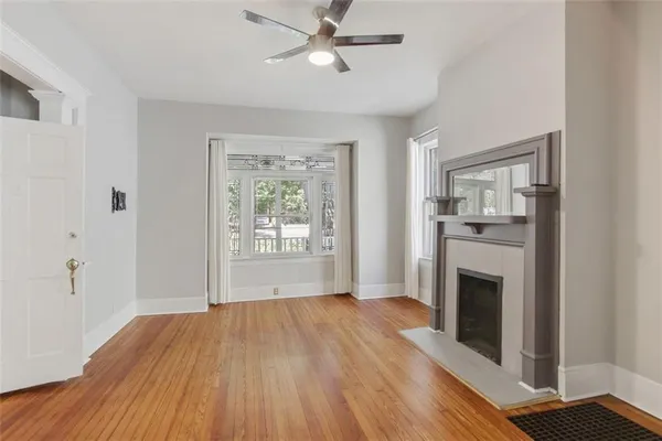 a view of an empty room with wooden floor fireplace and a window