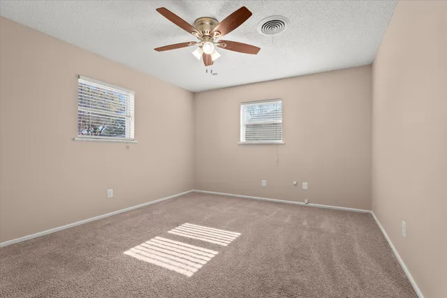 an empty room with a ceiling fan and a window