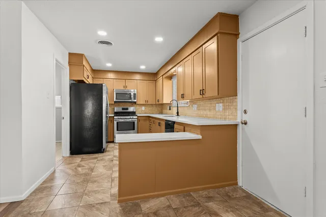 a kitchen with stainless steel appliances granite countertop a refrigerator and a stove