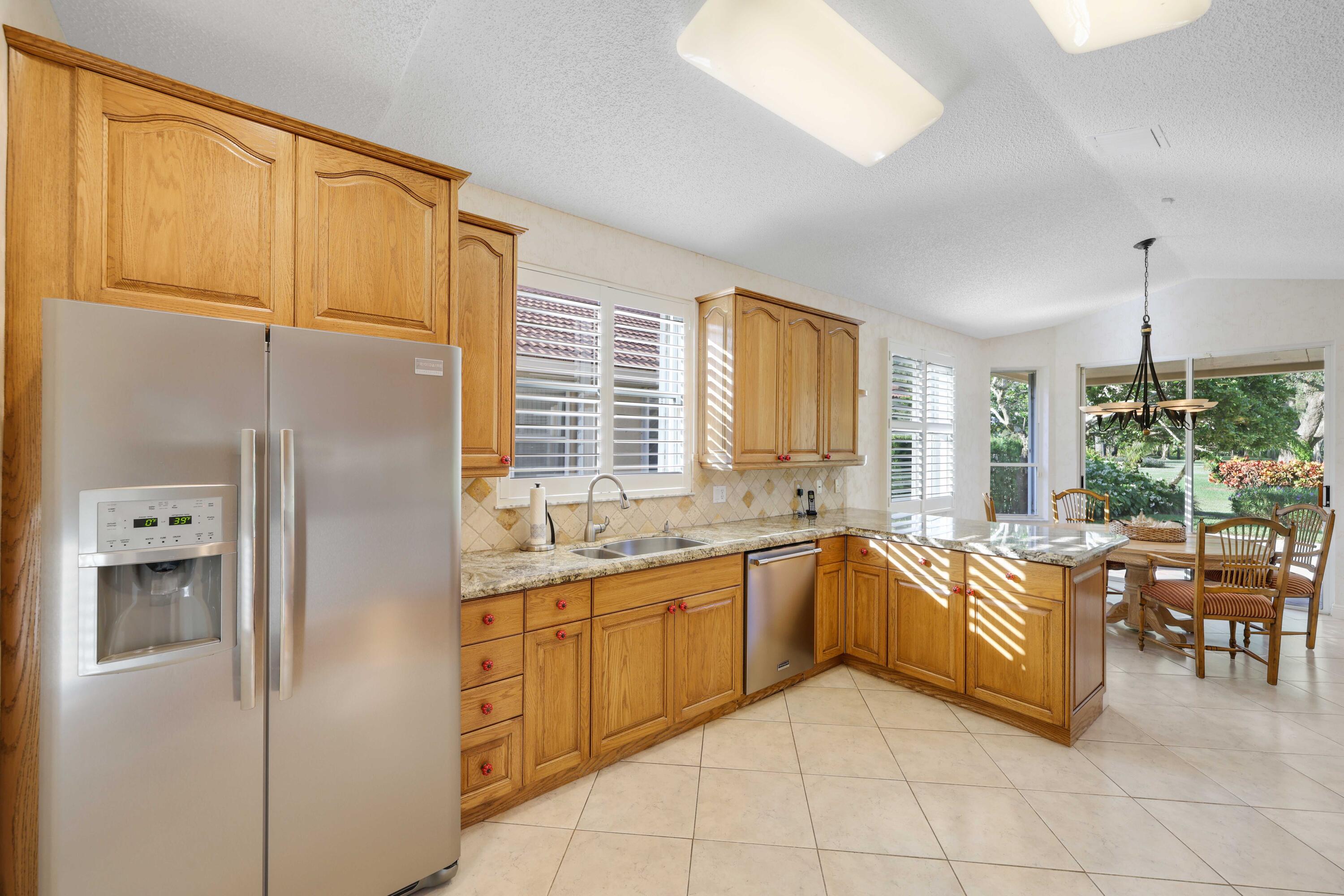 7633 La Corniche Circle Boca Raton, FL 33433 - Photo 18 of 49 a large white kitchen with granite countertop a refrigerator and a sink