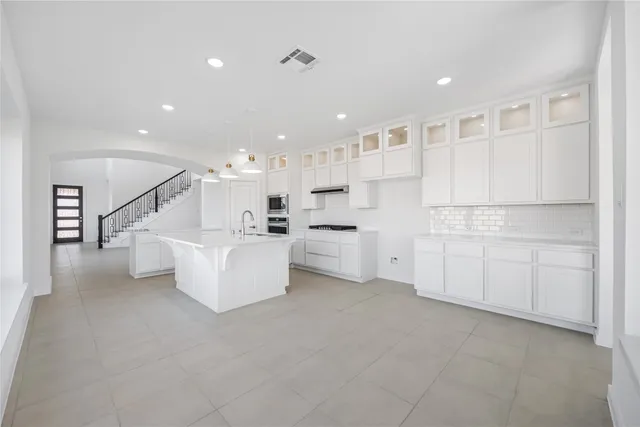 a large white kitchen with white cabinets and stainless steel appliances