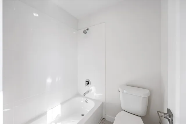 a white toilet sitting next to a bath tub