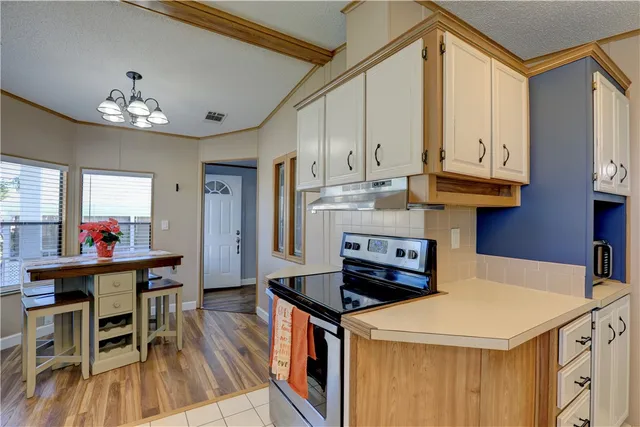 a kitchen with stainless steel appliances granite countertop a stove a refrigerator a kitchen island a dining table and chairs with wooden floor