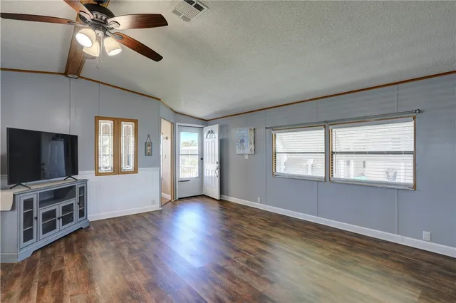 an empty room with wooden floor fan and windows