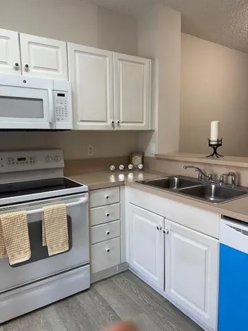 a kitchen with white cabinets and sink