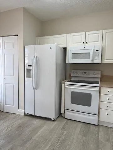 a kitchen with white cabinets and white appliances