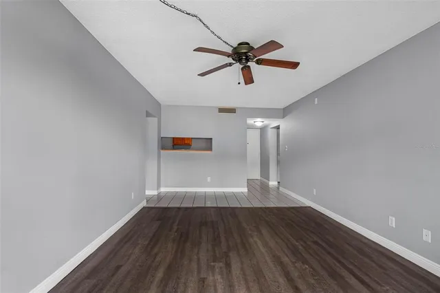 a view of empty room with wooden floor and fan