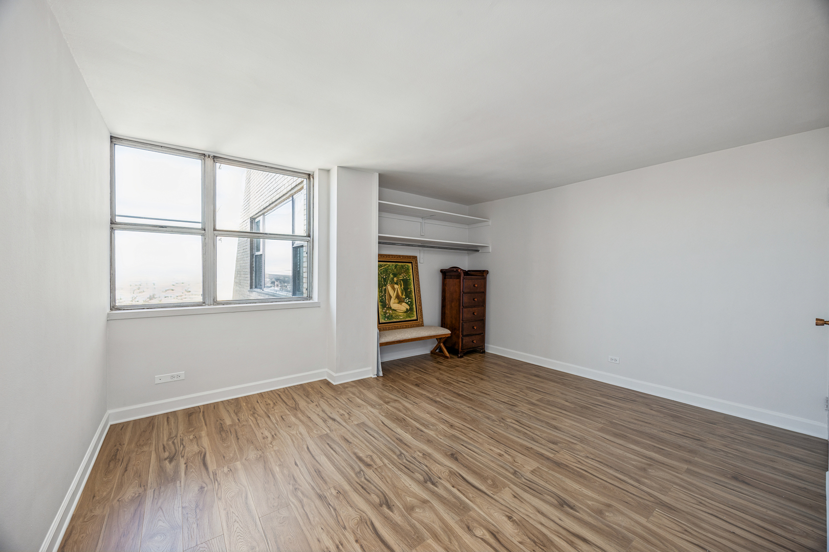 6301 North Sheridan Road, Unit 23J Chicago, IL 60660 - Photo 6 of 21 a view of an empty room with wooden floor and a window