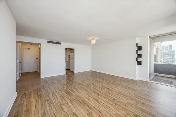 a view of an empty room with wooden floor and a window