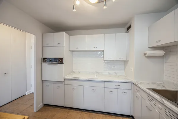 a kitchen with a sink a stove a refrigerator and white cabinets
