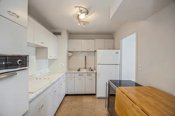 a kitchen with a sink a stove a refrigerator and white cabinets