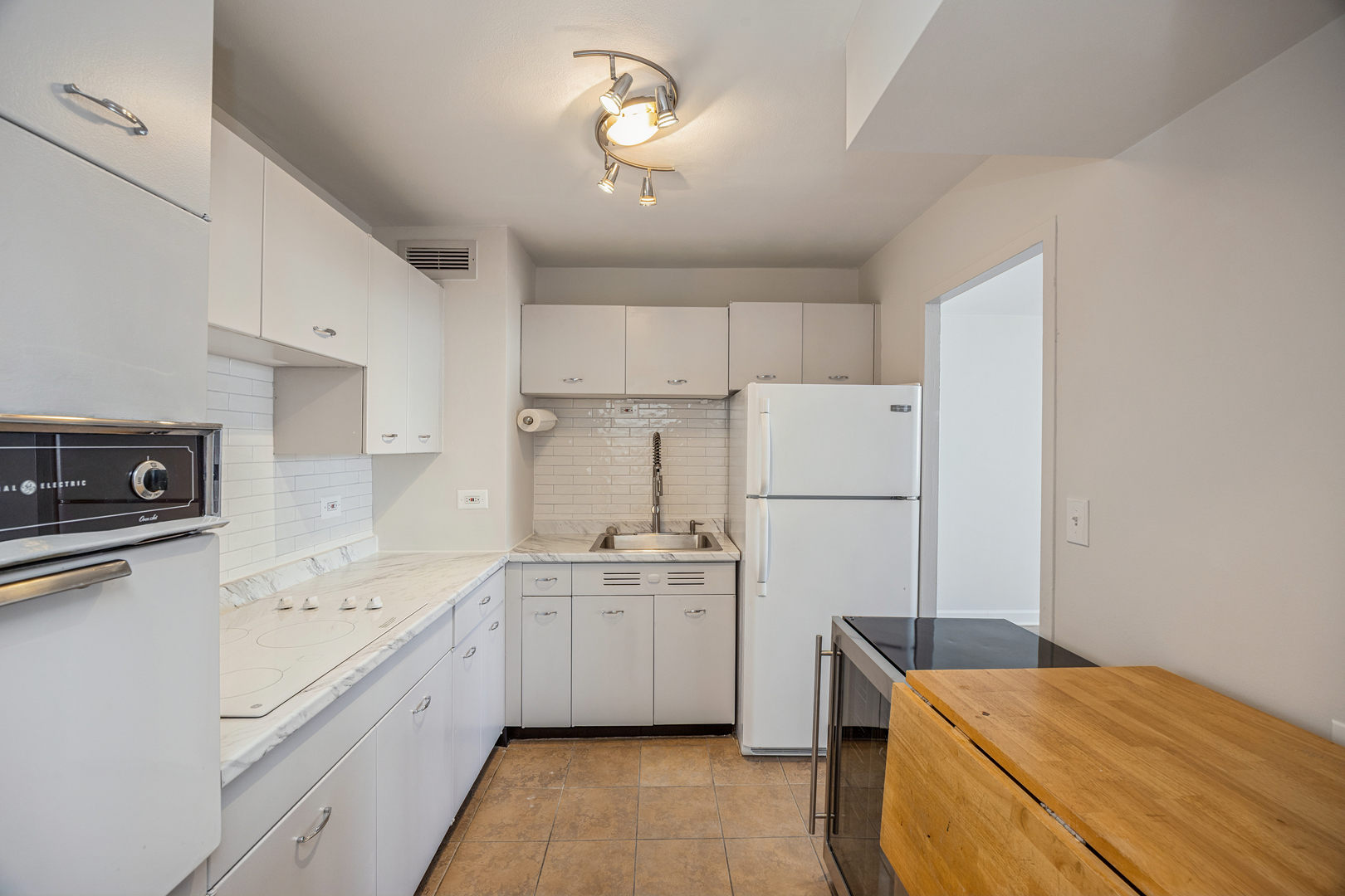 6301 North Sheridan Road, Unit 23J Chicago, IL 60660 - Photo 10 of 21 a kitchen with a sink a stove a refrigerator and white cabinets