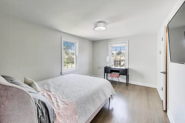 a bedroom with a bed table chair and a window