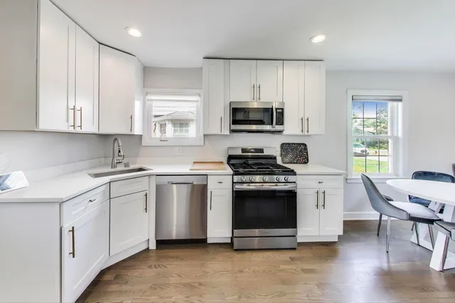 a kitchen with stainless steel appliances white cabinets a sink and a stove