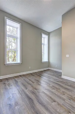 a view of an empty room with wooden floor and a window