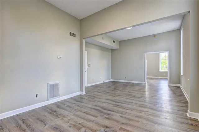 a view of an empty room with window and wooden floor