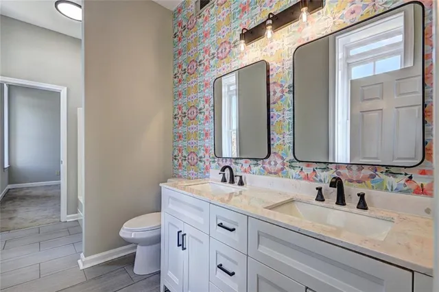 a bathroom with double vanity sink a mirror and a toilet