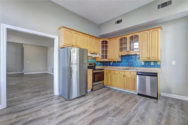 a kitchen with granite countertop wooden floors stainless steel appliances a sink and a window