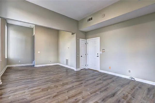 a view of an empty room with wooden floor and closet