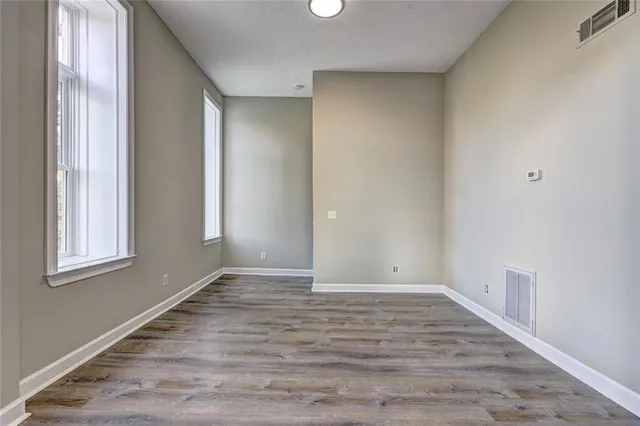 a view of an empty room with wooden floor and a window