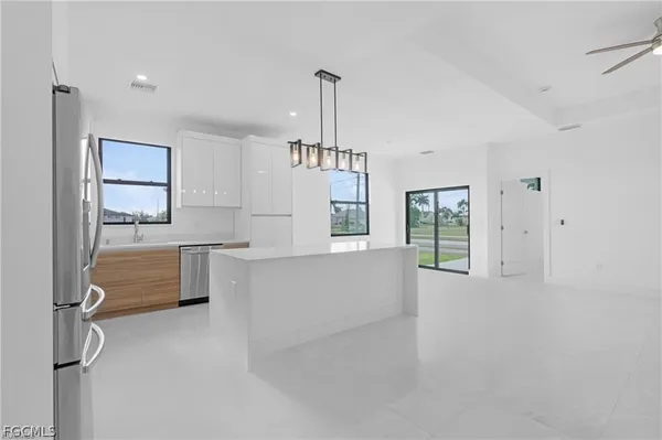 a large white kitchen with kitchen island a sink stainless steel appliances and cabinets
