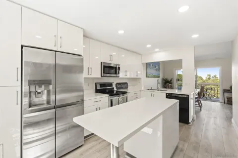a kitchen with stainless steel appliances a sink a stove a refrigerator cabinets and a window