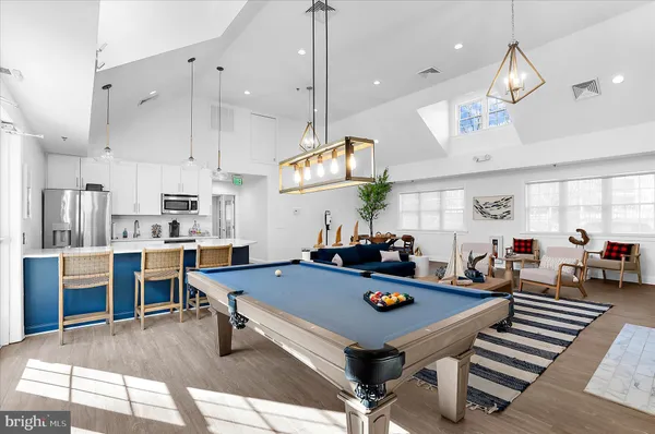 a room with wooden floor pool table and chairs
