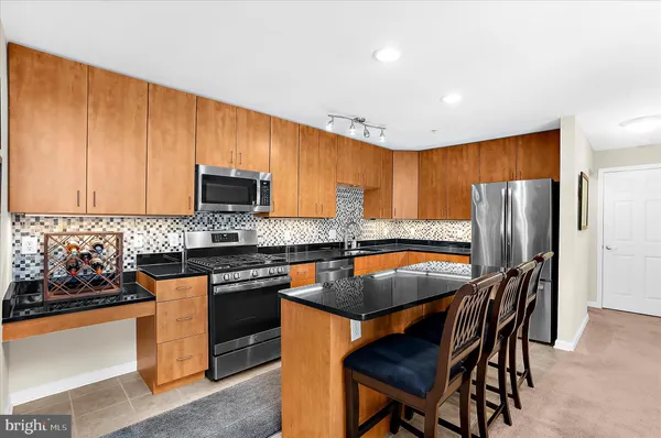 a kitchen with stainless steel appliances granite countertop a stove top oven a refrigerator a sink and a dining table with granite countertops