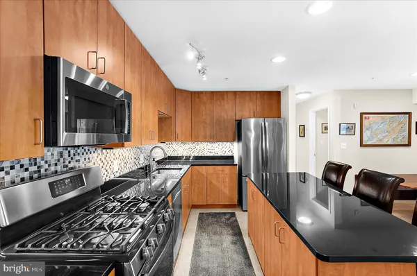 a kitchen with stainless steel appliances a table chairs and a refrigerator