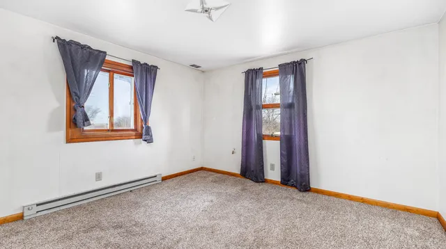 a view of an empty room with window and cabinet