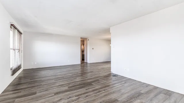 a view of an empty room with wooden floor and a window