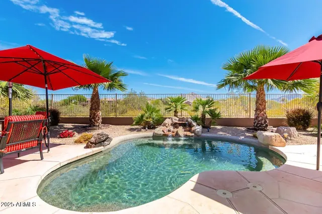a view of a swimming pool with a table and chairs under an umbrella