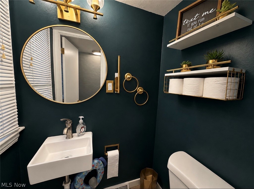 3714 Avalon Road Shaker Heights, OH 44120 - Photo 45 of 46 Compact bathroom featuring a wall-mounted rectangular sink with a single-handle faucet, a round gold-framed mirror, and a brass-finish vanity light fixture