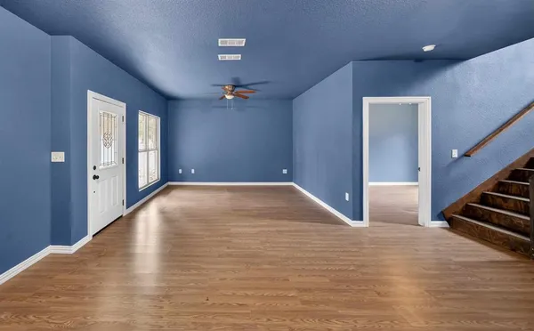 a view of an empty room with wooden floor and stairs