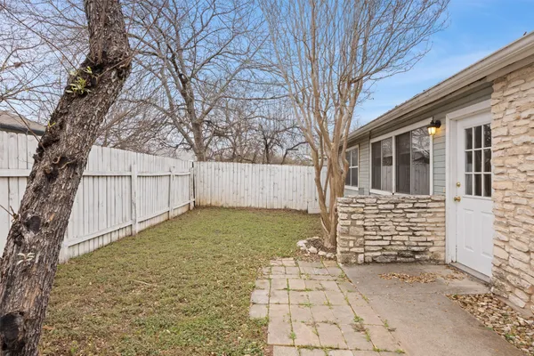 a view of white house with a large tree and wooden fence