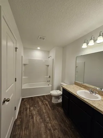 a bathroom with a granite countertop sink a toilet and shower