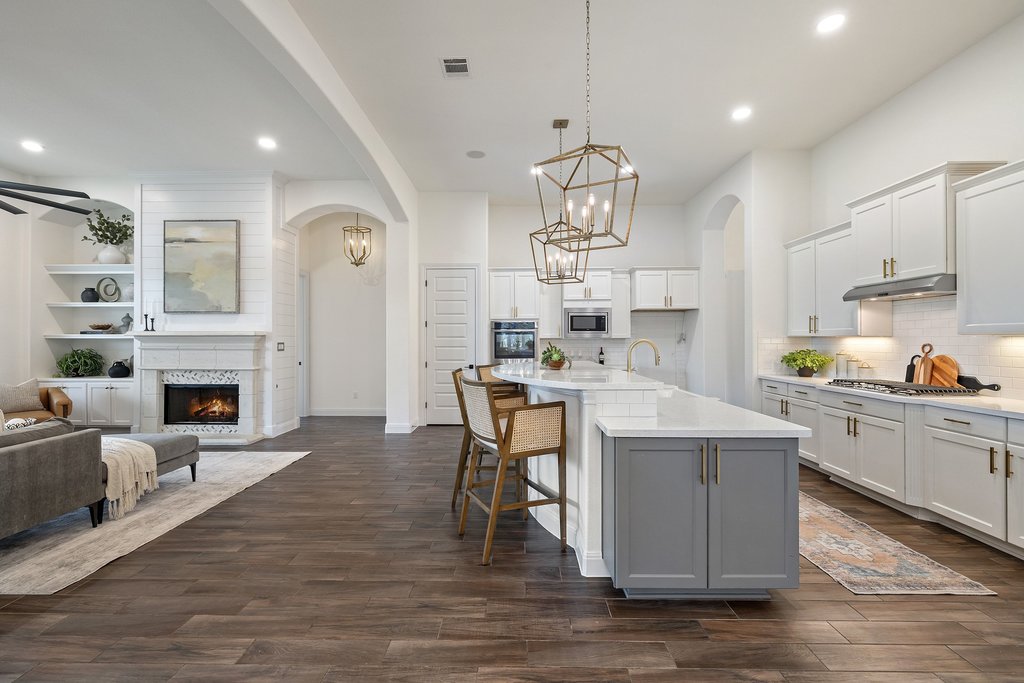 17641 Stratus Cove Dripping Springs, TX 78620 - Photo 39 of 40 Kitchen with open floor plan, a lit fireplace, a breakfast bar area, a kitchen island with sink, and suspended lighting