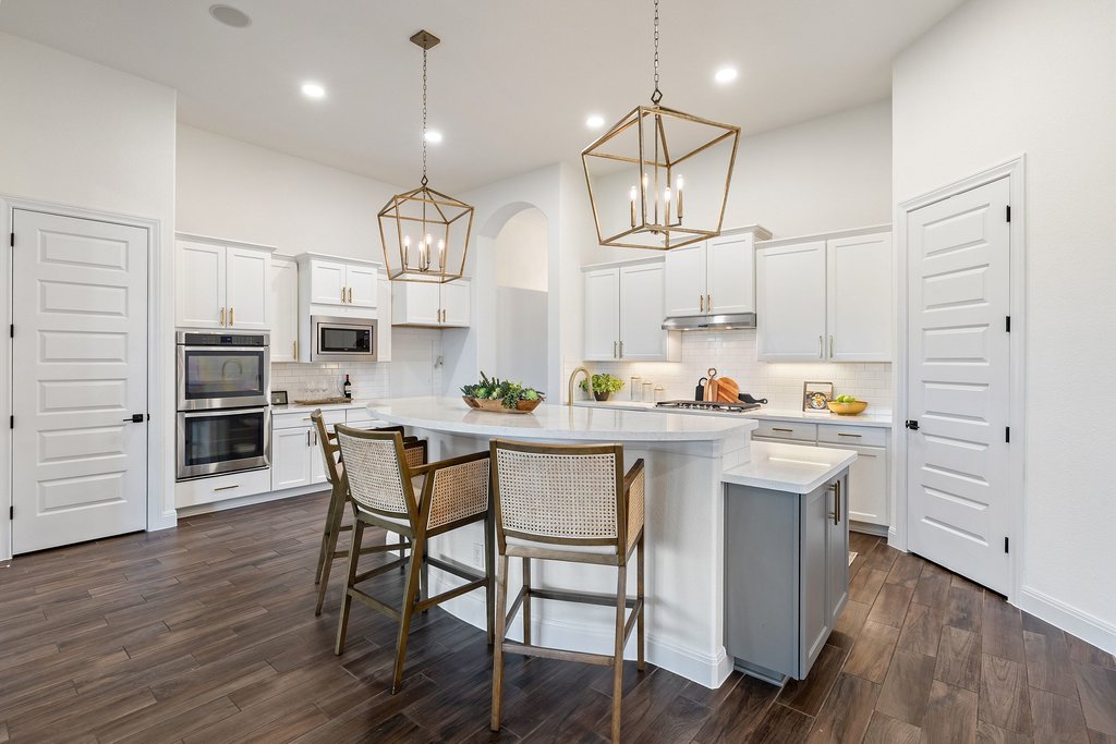 17641 Stratus Cove Dripping Springs, TX 78620 - Photo 12 of 40 Kitchen with white cabinets, a center island with sink, a kitchen breakfast bar, stainless steel appliances, and dark wood-type flooring