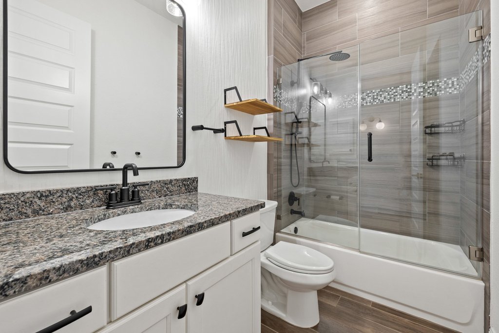 17641 Stratus Cove Dripping Springs, TX 78620 - Photo 25 of 40 Full bathroom with vanity, bath / shower combo with glass door, and wood tiled floors