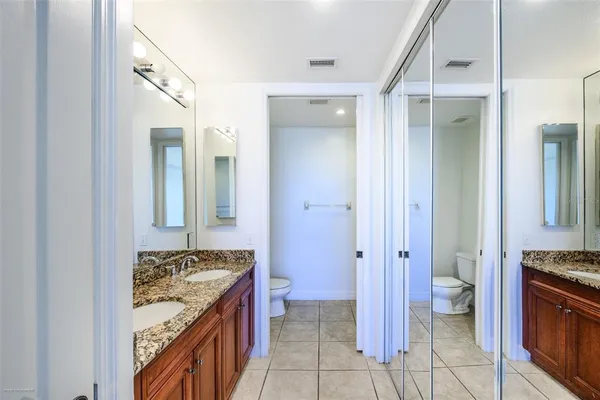 a bathroom with a granite countertop sink a toilet a mirror and shower