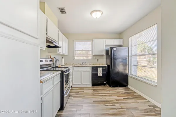 a kitchen with stainless steel appliances granite countertop a refrigerator a stove a sink and a window