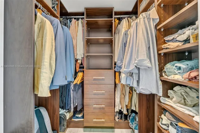 a view of walk in closet with clothes and shoes